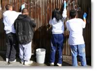 Photo of teenage kids painting a fence.