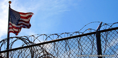 Image of barbed-wire fence with flag in the background