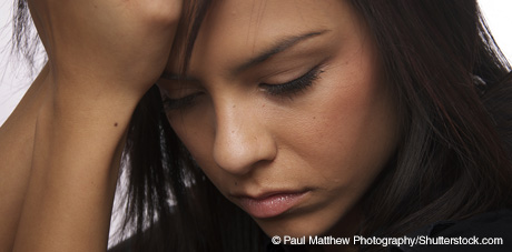 Female teenager holding head in hand