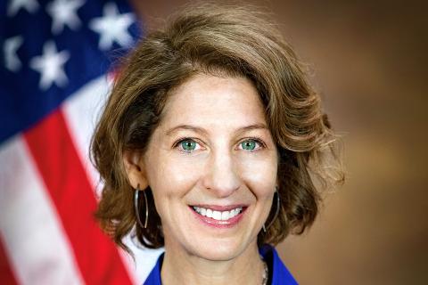 Amy L. Solomon, Assistant Attorney General Amy Solomon smiles in front of U.S. Flag in background